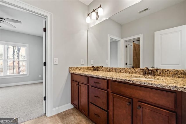 full bath with double vanity, visible vents, ceiling fan, a sink, and baseboards