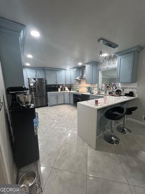 kitchen with wall chimney range hood, a breakfast bar, appliances with stainless steel finishes, decorative light fixtures, and kitchen peninsula