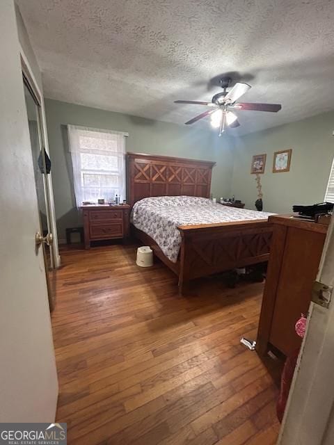 bedroom with ceiling fan, hardwood / wood-style floors, and a textured ceiling