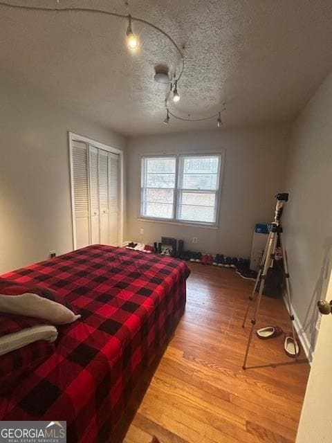 bedroom featuring wood-type flooring, a closet, and a textured ceiling