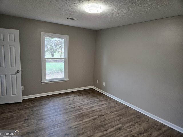 spare room featuring dark wood-type flooring and a textured ceiling