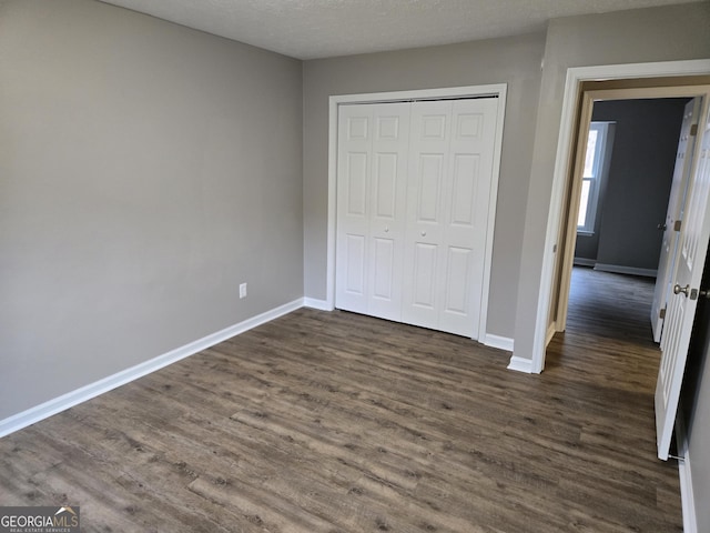 unfurnished bedroom featuring dark hardwood / wood-style floors, a textured ceiling, and a closet