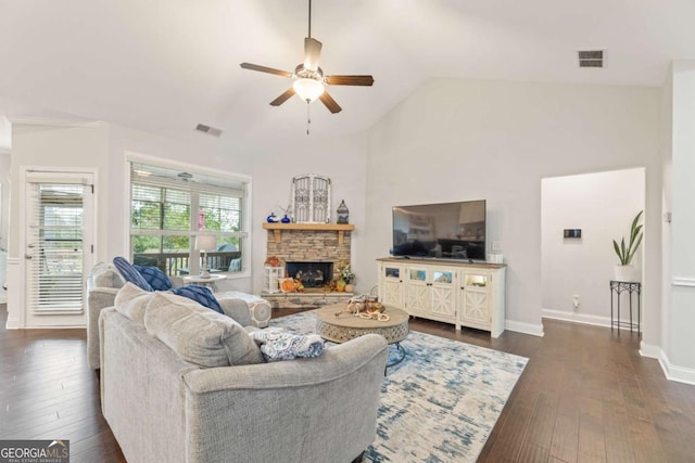 living room with a stone fireplace, dark hardwood / wood-style floors, lofted ceiling, and ceiling fan