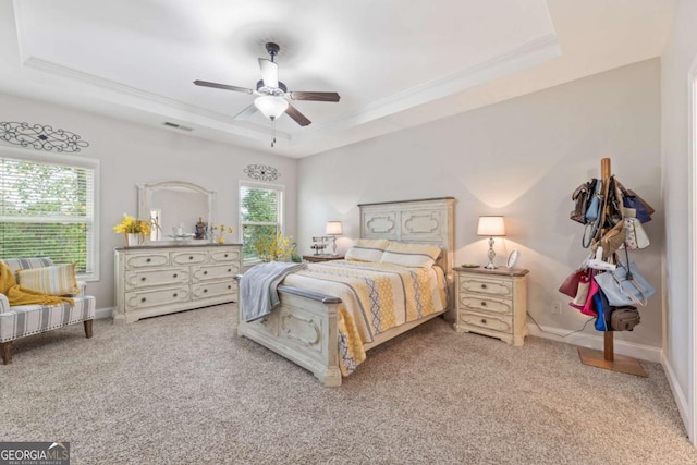 carpeted bedroom featuring a raised ceiling, ceiling fan, and multiple windows