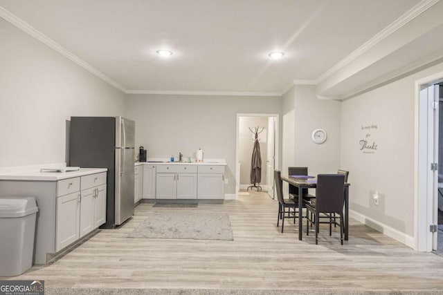 dining area featuring ornamental molding, sink, and light wood-type flooring