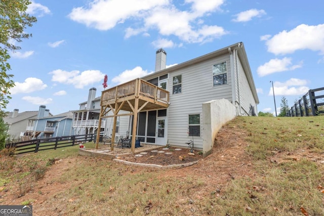 rear view of house with a wooden deck, a sunroom, and a lawn