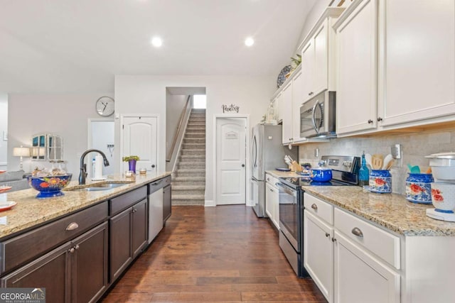 kitchen featuring sink, appliances with stainless steel finishes, white cabinetry, light stone counters, and tasteful backsplash