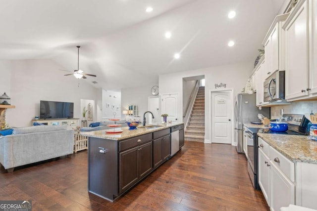 kitchen with sink, dark brown cabinets, stainless steel appliances, white cabinets, and a center island with sink