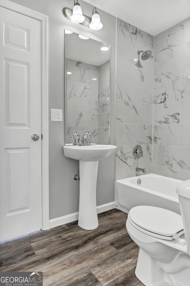 bathroom featuring wood-type flooring, toilet, and tiled shower / bath combo