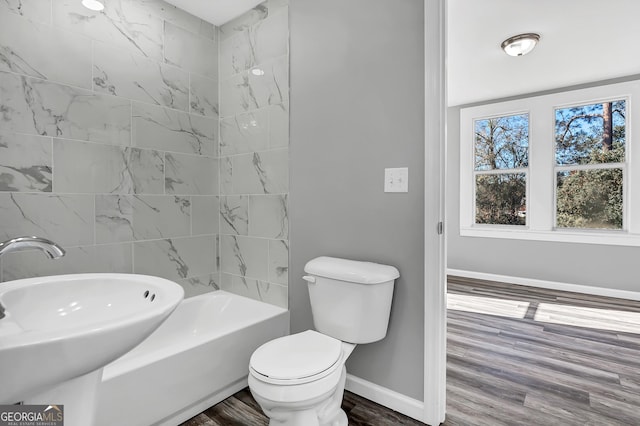 full bathroom featuring hardwood / wood-style flooring, toilet, bathing tub / shower combination, and sink