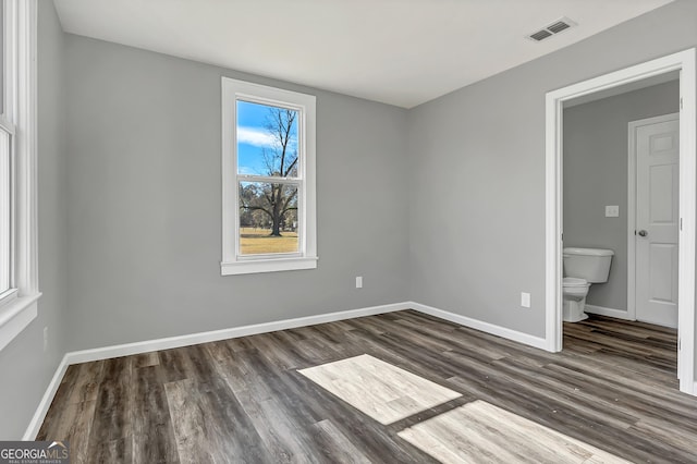 unfurnished bedroom with dark wood-type flooring and ensuite bath