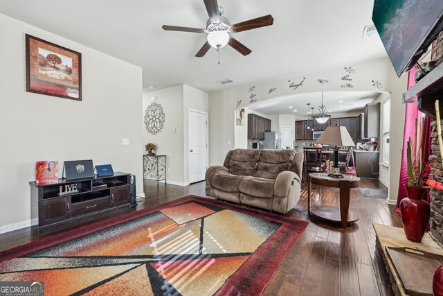 living room with hardwood / wood-style flooring, a stone fireplace, and ceiling fan