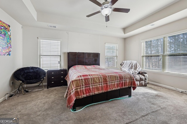 carpeted bedroom featuring ceiling fan and a raised ceiling