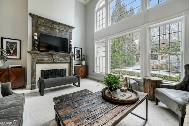 carpeted living room featuring a tiled fireplace and a towering ceiling