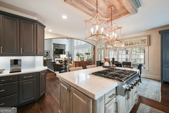 kitchen featuring a kitchen island, white cabinets, stainless steel gas cooktop, a tray ceiling, and dark wood-type flooring