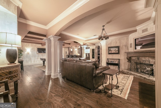 living room featuring dark wood-type flooring, ornamental molding, a fireplace, and ornate columns