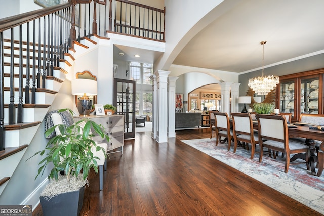 dining space with french doors, crown molding, a chandelier, dark hardwood / wood-style flooring, and decorative columns