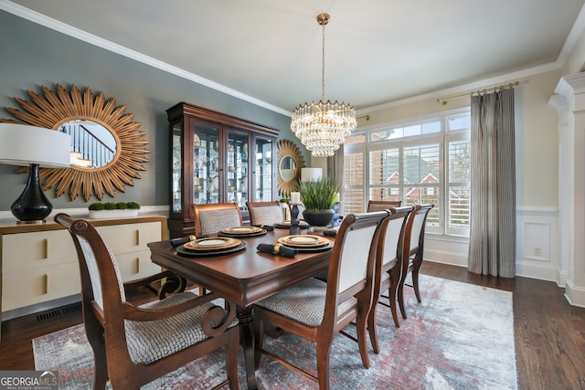 dining room featuring an inviting chandelier, dark wood-type flooring, ornamental molding, and ornate columns