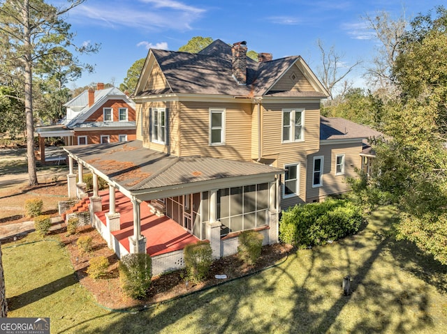 rear view of house featuring a lawn and a sunroom