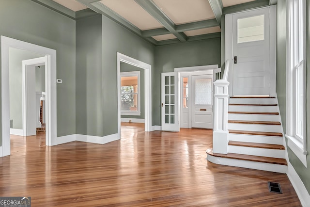 interior space featuring a healthy amount of sunlight, coffered ceiling, beam ceiling, and light hardwood / wood-style flooring