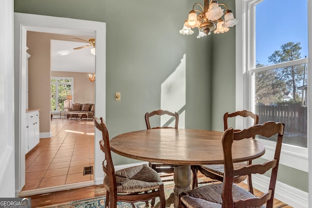 tiled dining space with ceiling fan with notable chandelier