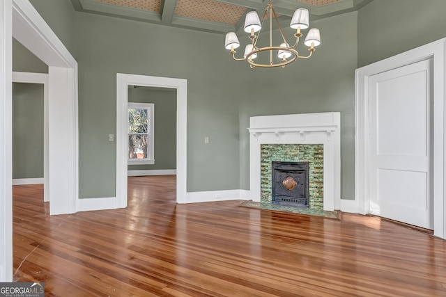 unfurnished living room with an inviting chandelier, hardwood / wood-style flooring, ornamental molding, and a high ceiling