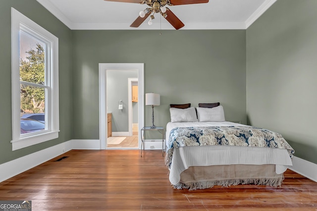 bedroom featuring hardwood / wood-style flooring, ensuite bathroom, ornamental molding, and ceiling fan