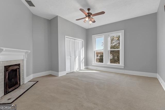 unfurnished living room featuring ceiling fan, light carpet, a textured ceiling, and a fireplace