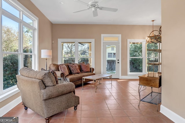 tiled living room featuring ceiling fan with notable chandelier and plenty of natural light