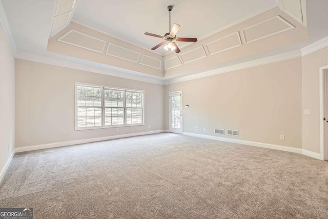 carpeted empty room with ceiling fan, ornamental molding, and a raised ceiling