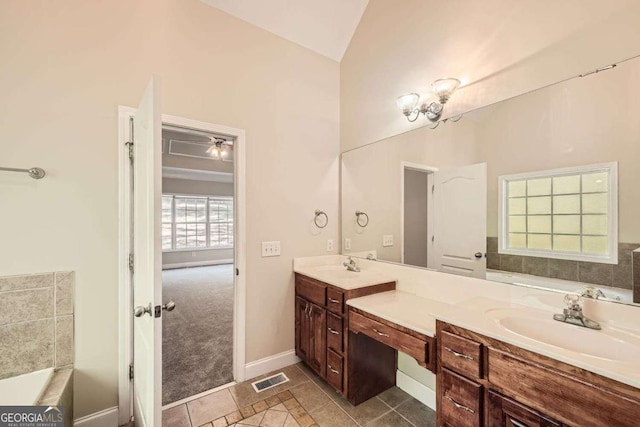 bathroom with a bathing tub, vanity, vaulted ceiling, and tile patterned floors