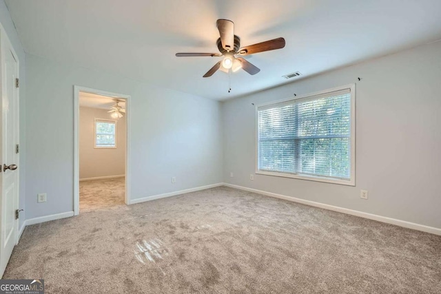 unfurnished room featuring ceiling fan, plenty of natural light, and light carpet