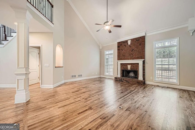 unfurnished living room with ornate columns, ornamental molding, a brick fireplace, and a wealth of natural light