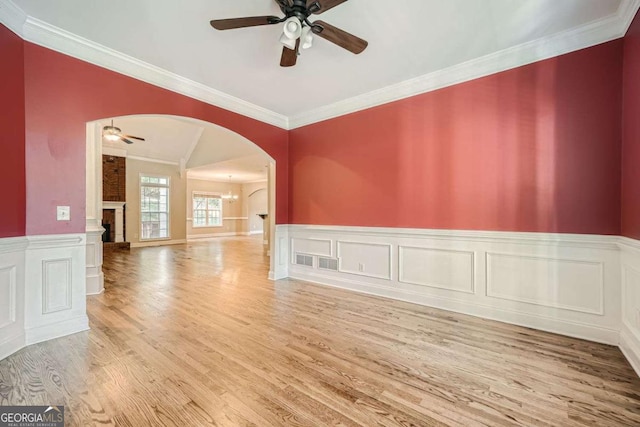 empty room featuring ornamental molding, wood-type flooring, ceiling fan with notable chandelier, and lofted ceiling