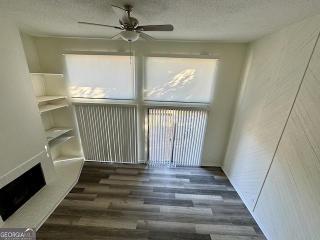 empty room with dark wood-type flooring, a textured ceiling, and ceiling fan