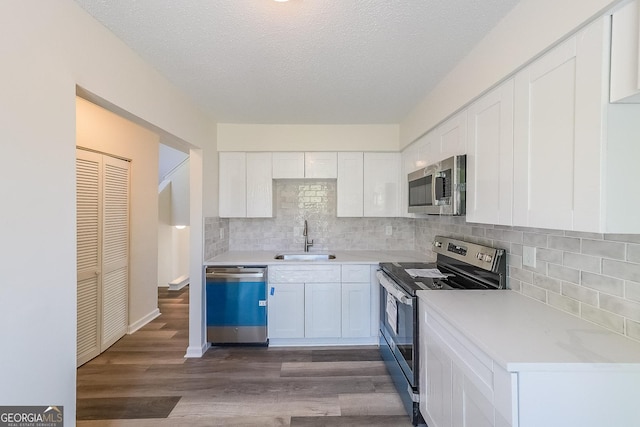 kitchen featuring dark wood-type flooring, sink, a textured ceiling, appliances with stainless steel finishes, and white cabinets