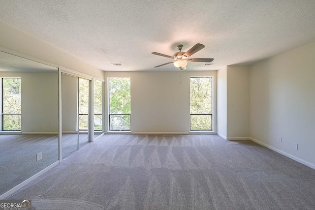 spare room featuring ceiling fan, carpet flooring, and a textured ceiling