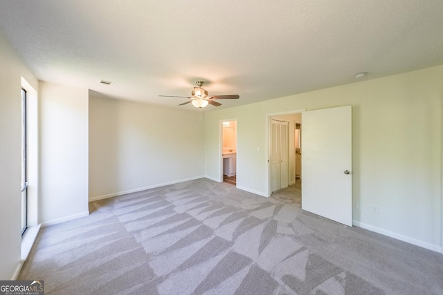 spare room featuring ceiling fan, light colored carpet, and a textured ceiling