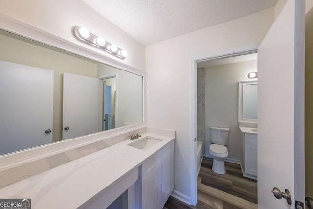 bathroom with hardwood / wood-style floors, vanity, a washtub, toilet, and a textured ceiling