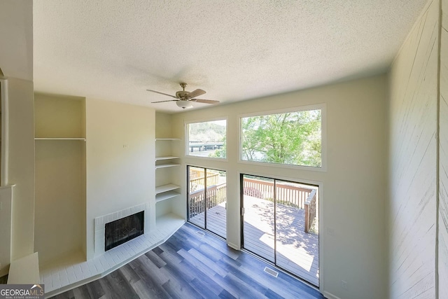 unfurnished living room featuring hardwood / wood-style flooring, a fireplace, heating unit, and a textured ceiling