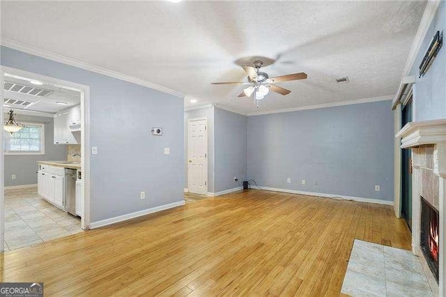 unfurnished living room featuring crown molding, a textured ceiling, light wood-type flooring, a tile fireplace, and ceiling fan