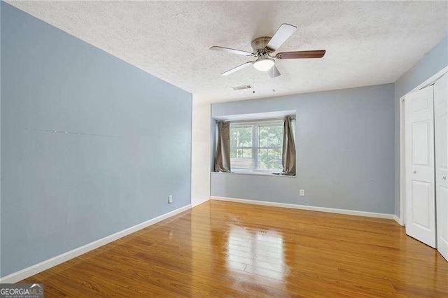 unfurnished bedroom featuring hardwood / wood-style floors, a textured ceiling, a closet, and ceiling fan