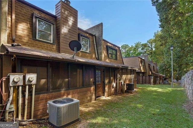 rear view of property with central AC and a lawn