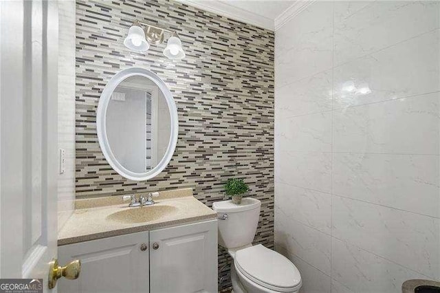 bathroom featuring ornamental molding, tile walls, vanity, and toilet