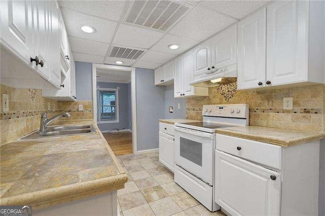 kitchen featuring sink, white cabinets, electric stove, decorative backsplash, and a drop ceiling