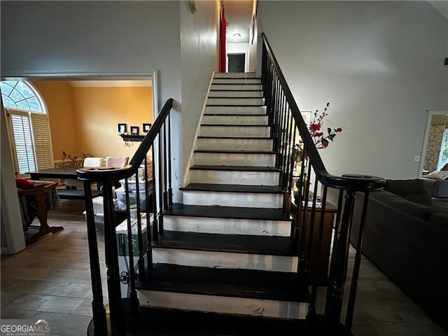 stairs with a towering ceiling and wood-type flooring