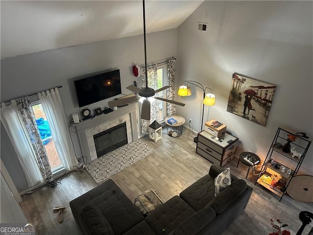 living room with a tiled fireplace, hardwood / wood-style floors, and high vaulted ceiling