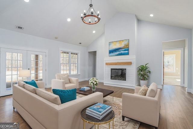 living room featuring high vaulted ceiling, french doors, a chandelier, and light wood-type flooring