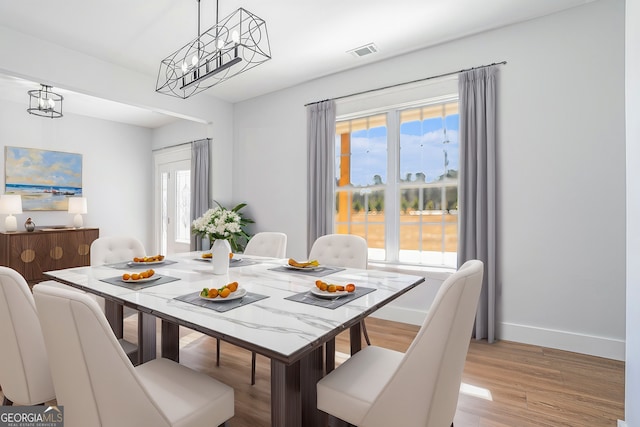 dining space with a notable chandelier and light wood-type flooring