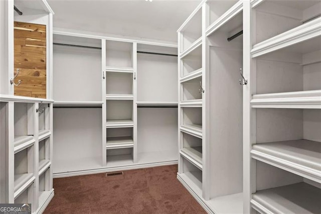 walk in closet featuring dark colored carpet